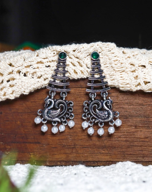 Pair of silver-toned oxidised peacock-themed earrings with emerald green stone on top