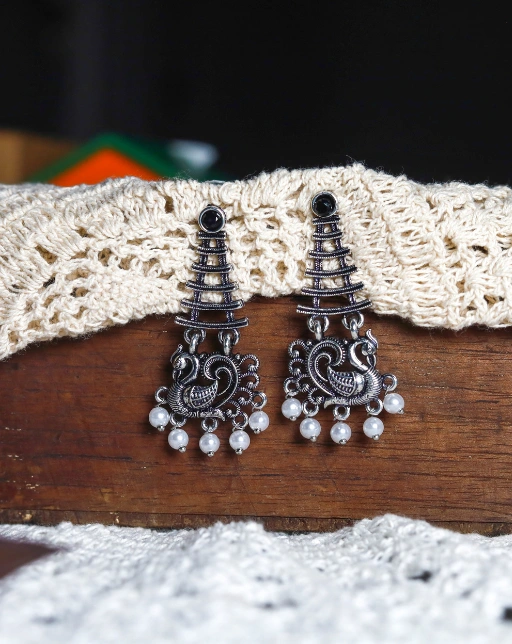 Pair of silver-toned oxidised peacock-themed earrings with emerald black stone on top